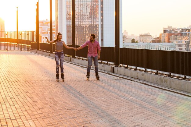 Couple holding hands and rollerblading people on sunrise city background our road to happiness