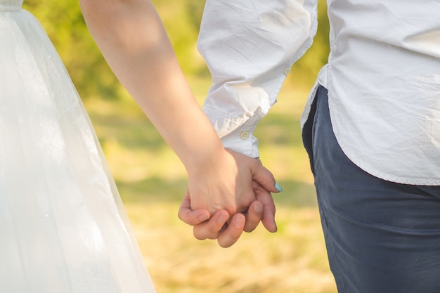 Couple holding hands during their stroll Close up on hands of man and woman in sunny summer day