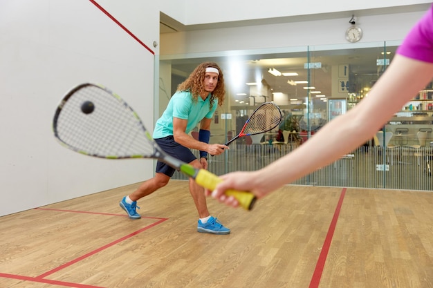 Photo couple holding squash racquets playing game match at fitness studio athletic man and woman recreation concept