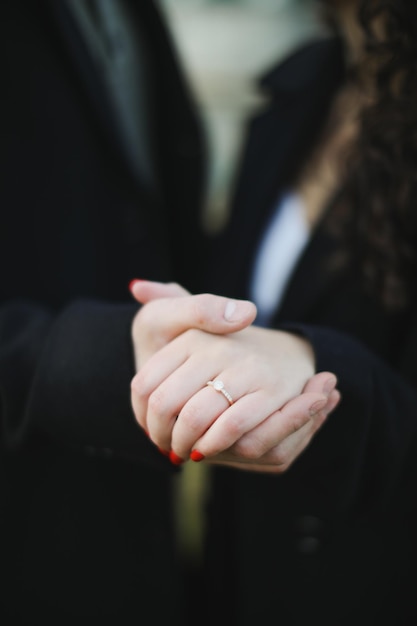 A couple holds hands with a ring on their finger.