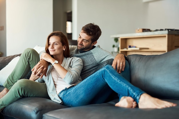 Photo couple home and happy on couch in living room for bonding care and support as lovers house affection and smile as lover for relationship on sofa in love on break relax and rest in comfort