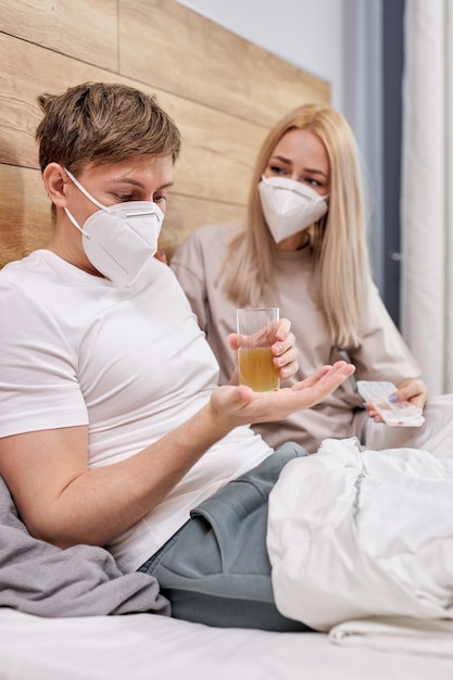 Couple at home with seasonal winter cold illness disease lie on bed taking medications, support and help each other, at home. coronavirus, covid-19, sickness concept