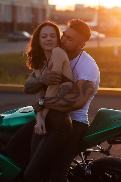 Couple hugging near motorbike at sunset