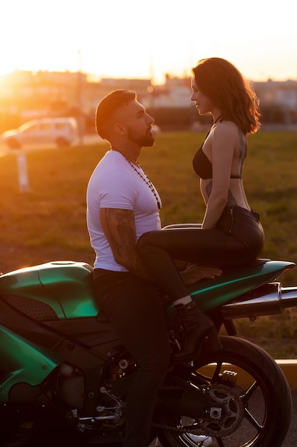 Couple hugging near motorbike at sunset