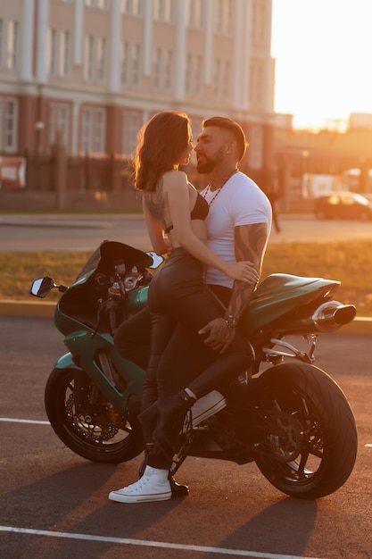 Couple hugging near motorbike at sunset