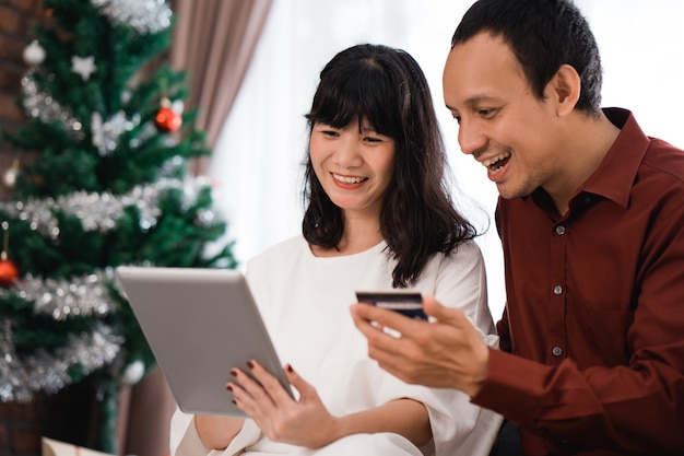 Couple hunt for christmas sale deal in online market. modern shopping using credit card payment