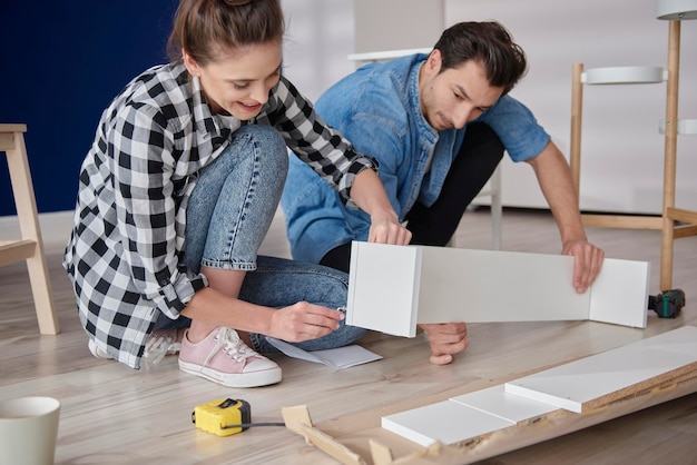 Couple installing bookshelf for new house