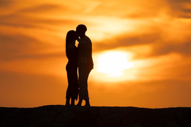 Photo a couple is kissing in front of a sunset