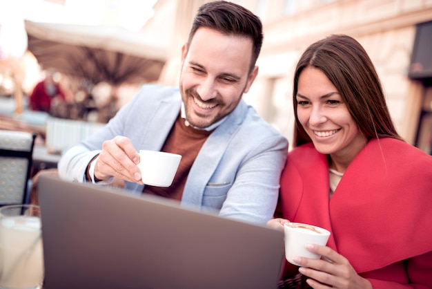 Couple is sitting at cafe and using a laptop