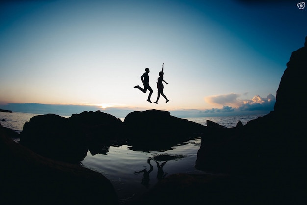 Couple jumping with some rocks underneath