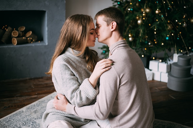 Couple kissing near Christmas tree at home, New Year