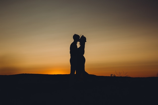 Couple kissing at sunset.