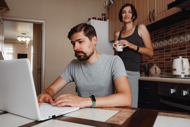 Couple at kitchen reading news and using laptop