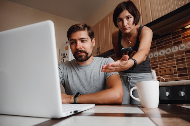 Couple at kitchen reading news and using laptop