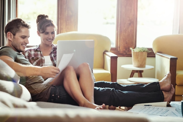 Photo couple laptop and home in lounge document and reading of bills marriage and smile in weekend and morning house man and woman on sofa paperwork and together in living room couch and happy