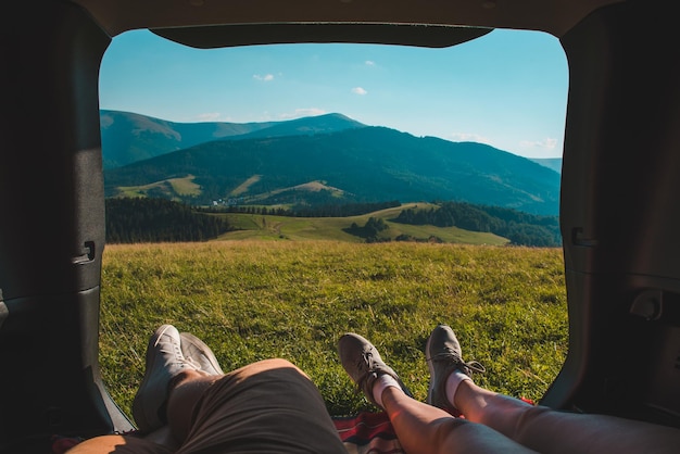 Couple laying in car trunk with beautiful view of mountains