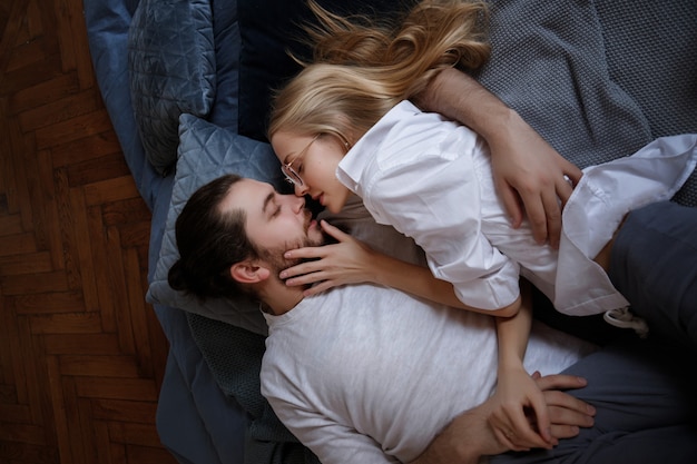 Couple lies on the bed and kisses