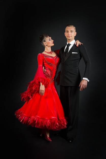 Couple in love, ballroom dance couple in red dress and black tuxedo on dark background. Valentines day concept. Love, proposal, date. Valentine, valentines, holiday, celebration.