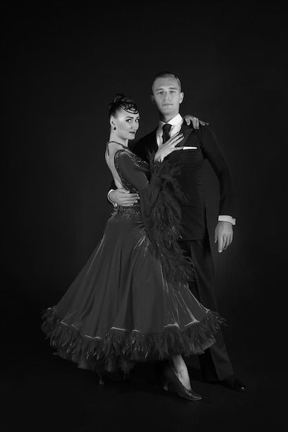 Couple in love ballroon dance couple in red dress and black tuxedo on black background