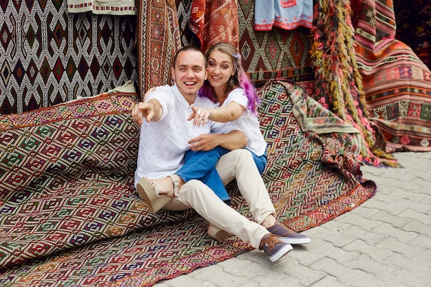 Couple in love buys a carpet and handmade textiles at an oriental market in Turkey. Hugs and cheerful happy faces of men and women