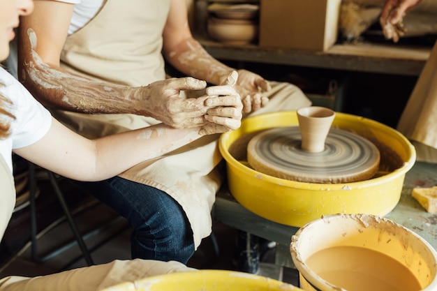 A couple in love creates a joint cup in a pottery workshop Potter making ceramic pot on the pottery wheel