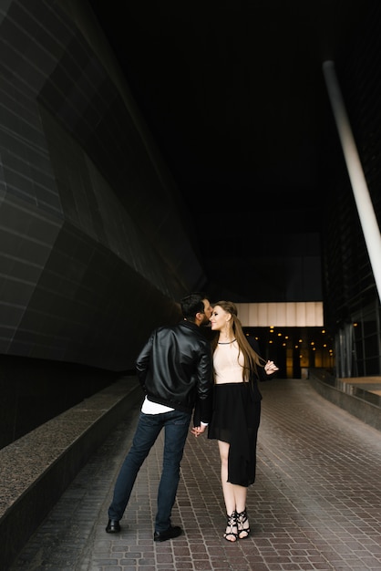 A couple in love in dark formal clothes walk around the city