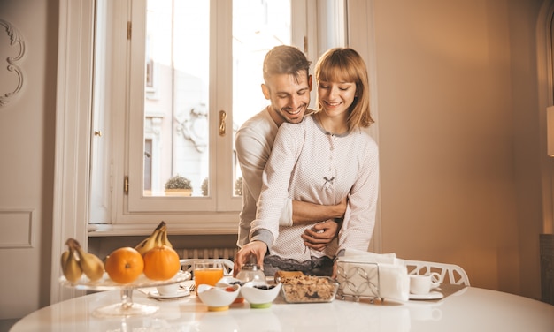 Couple in love eating breakfast early in the morning in the kitchen at home and having a good time.