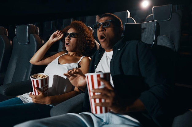 A couple in love friends watching a movie with popcorn in the cinema