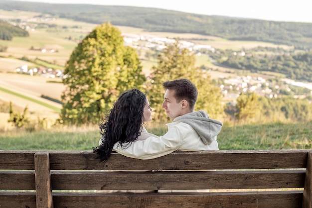 A couple in love, a guy and a girl sit on a bench and caress each other, kiss