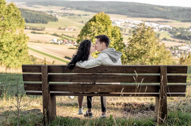 A couple in love, a guy and a girl sit on a bench and caress each other, kiss