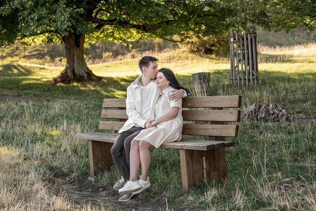 A couple in love, a guy and a girl sit on a bench and caress each other, kiss