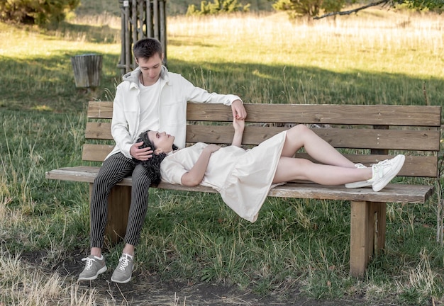 A couple in love, a guy and a girl sit on a bench and caress each other, kiss