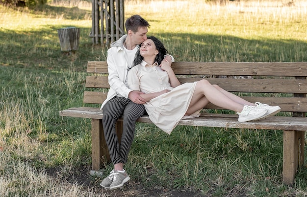 A couple in love, a guy and a girl sit on a bench and caress each other, kiss