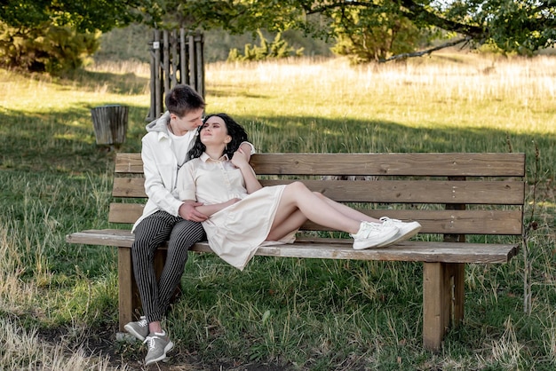 A couple in love, a guy and a girl sit on a bench and caress each other, kiss