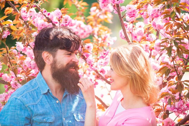 Couple in love having a date in spring blooming park on a spring day with beautiful cherry blossoms in the background.