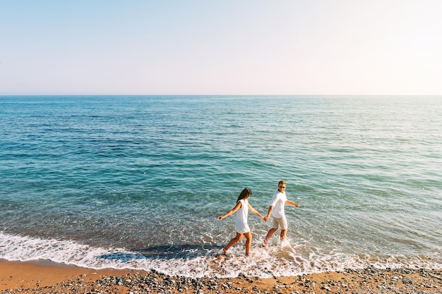 Couple in love having fun on the beach. Honeymoon trip. The couple are traveling. Man and woman on the beach. Happy couple. Run along the shore. Sea tour. Man and woman at sea. Wedding travel. Lovers