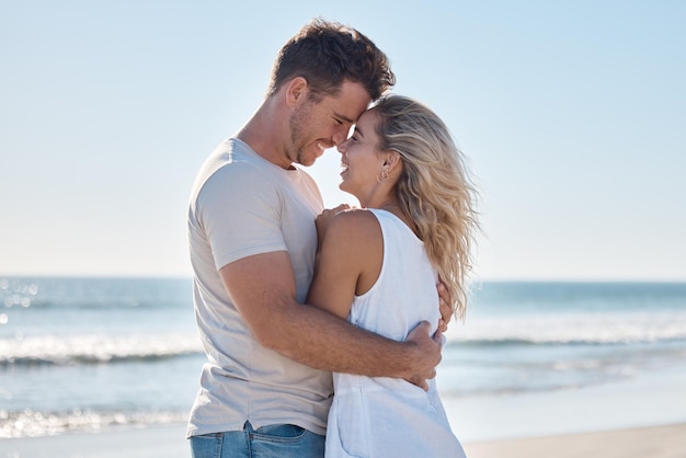 Couple love and hug in relationship at the beach for summer vacation or romantic bonding in the outdoors Happy man and woman hugging with smile together in loving embrace for romance by the ocean