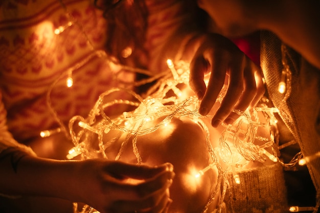 Couple in love hugging by night before Christmas. Loving embrace, light Christmas garland. Guy and woman love each other