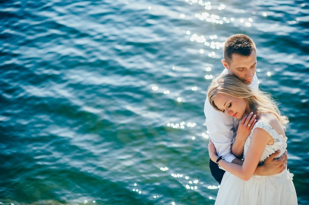 Couple in love hugging on a tropical beach with a turquoise water in the background