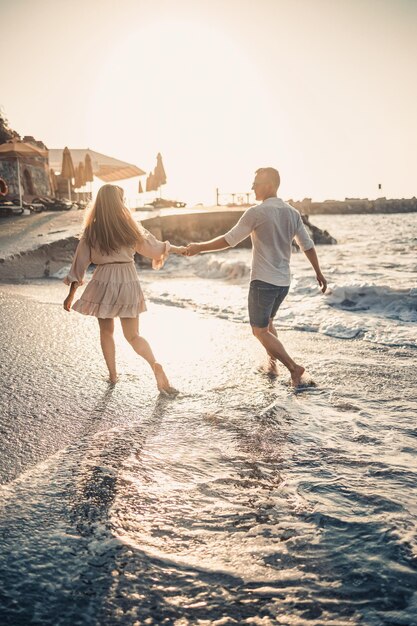 A couple in love is walking on the beach near the sea Young family at sunset by the mediterranean sea Summer vacation concept Selective focus