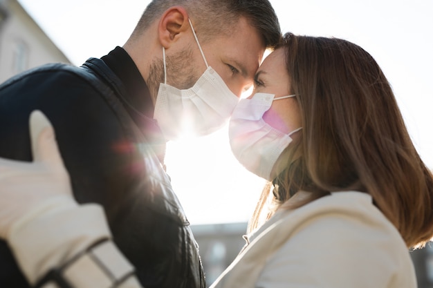 Couple in love, man and woman kissing each other in protective medical mask on face. Guy, girl against pandemic coronavirus, virus protection. Covid19