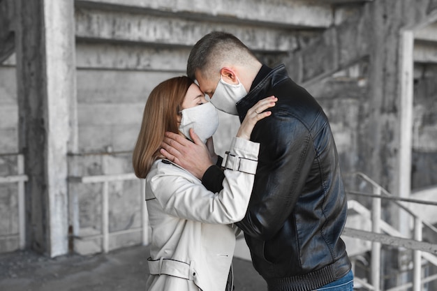 Couple in love, man and woman kissing each other in protective medical mask on face. Guy, girl against pandemic coronavirus, virus protection. Covsd19