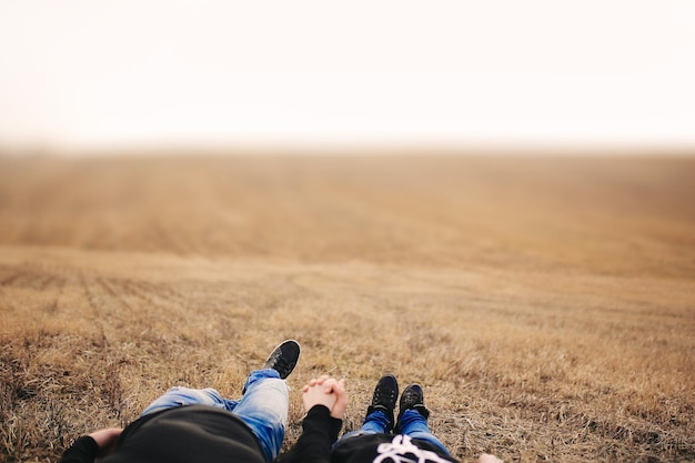 Photo couple in love man and woman lying in field holding hands concept of love autumn mood place for inscription