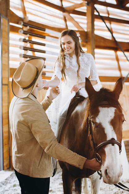 Couple in love riding horses on ranch at sunset in winter