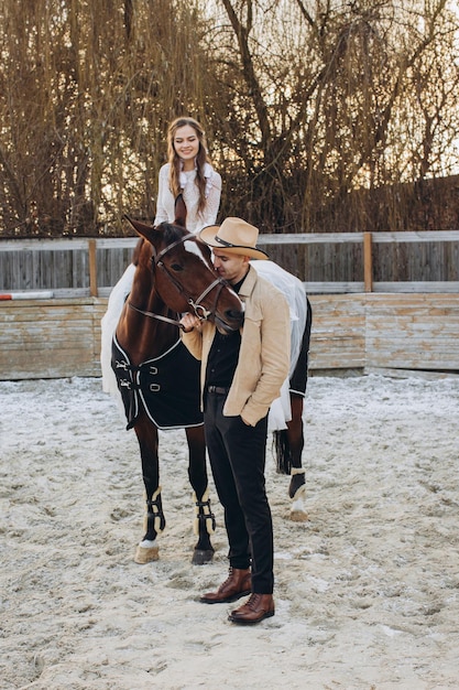 Couple in love riding horses on ranch at sunset in winter