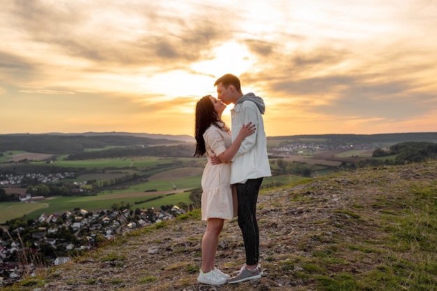 A couple in love stands on a mountain at sunset