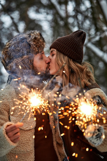 Couple Love Story in Snow Forest Kissing and Holding Sparklers Couple in Winter Nature Couple Celebrating Valentine's day date