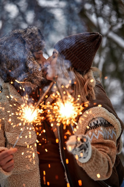 Couple Love Story in Snow Forest Kissing and Holding Sparklers Couple in Winter Nature Couple Celebrating Valentine's day date