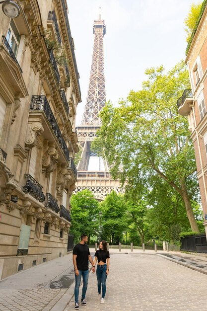 Couple in love walking hand in hand with the Eiffel Tower behind them in Paris