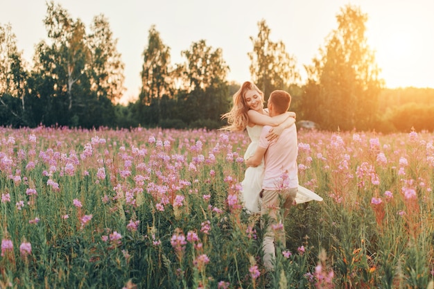 a couple in love walks through a flower meadow. Love and spring blooming. a man embraces a woman